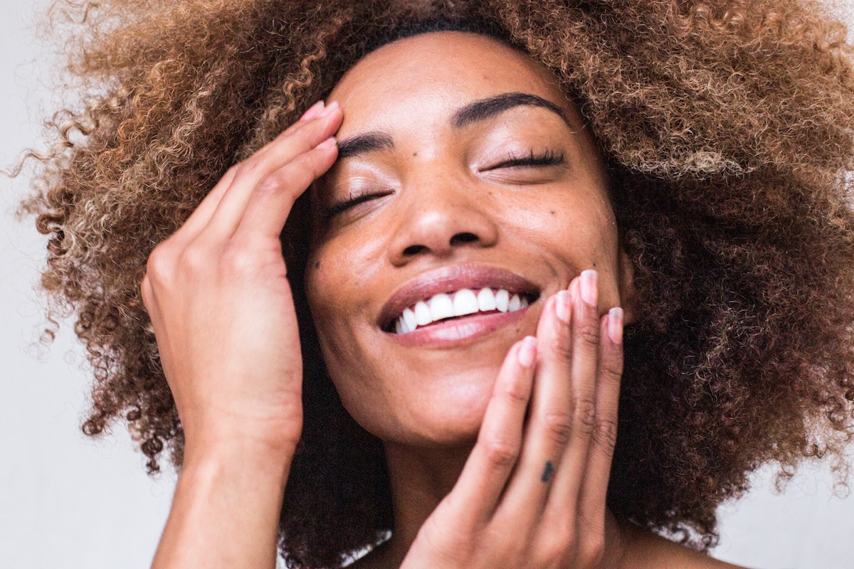 Black woman with clear skin smiling with eyes closed