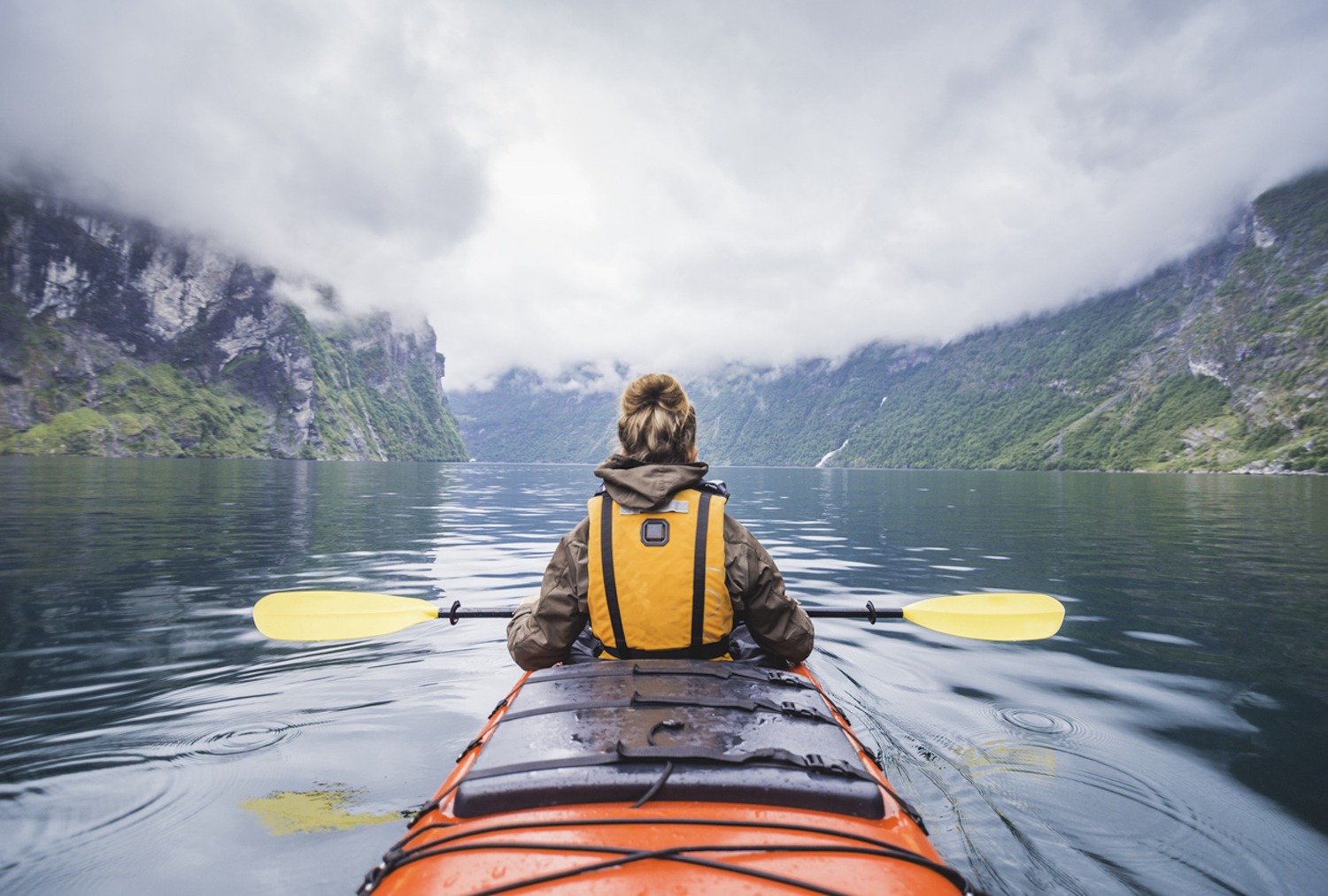 Woman kayaking in Geiranger fjord in Norway