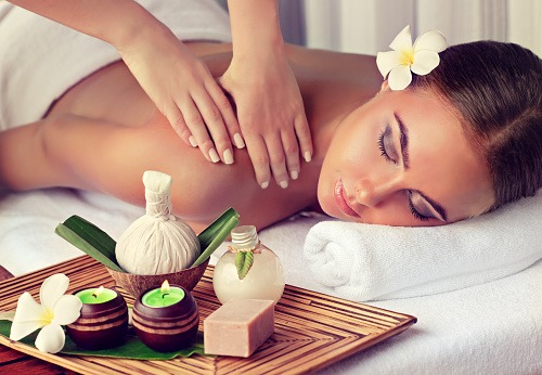 Young lady is laying on massage table and gets massage treatment. Spa and body massage. Woman is getting massage in the spa salon.